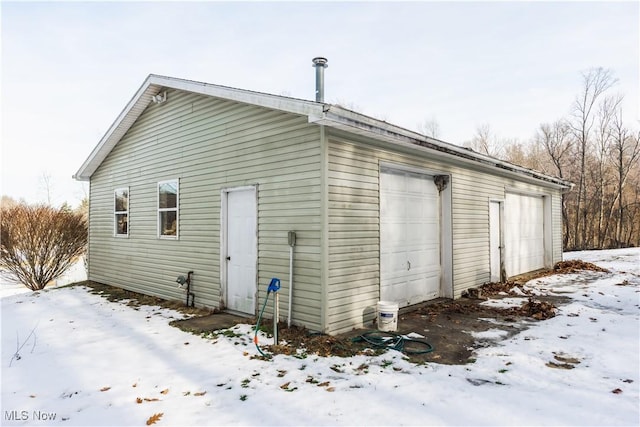 snow covered structure featuring a garage