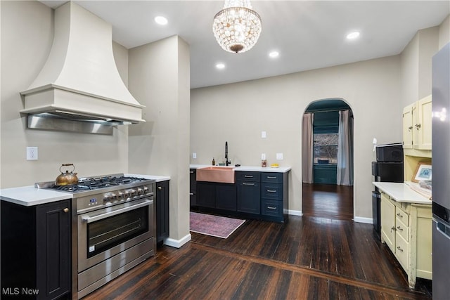 kitchen featuring sink, premium range hood, dark hardwood / wood-style floors, a notable chandelier, and high end stainless steel range