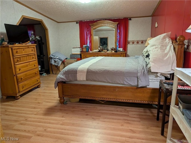 bedroom featuring crown molding, light hardwood / wood-style flooring, and a textured ceiling