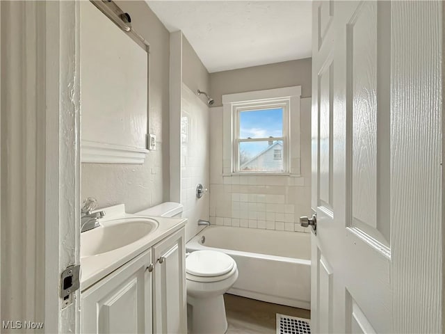 full bathroom with vanity, tiled shower / bath, hardwood / wood-style floors, and toilet