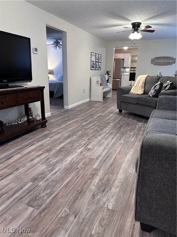 living room with hardwood / wood-style flooring, a textured ceiling, and ceiling fan