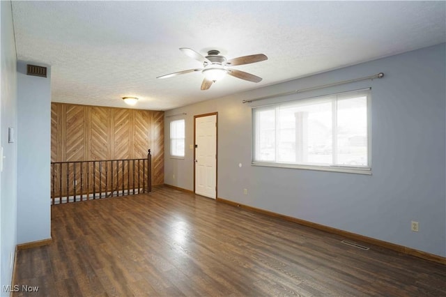 spare room featuring ceiling fan, dark wood-type flooring, and a textured ceiling