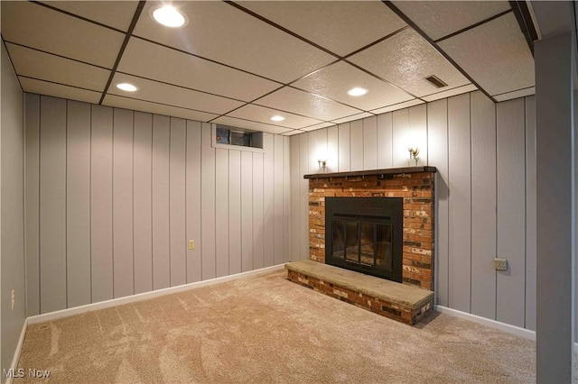 unfurnished living room featuring a paneled ceiling, a fireplace, and light carpet