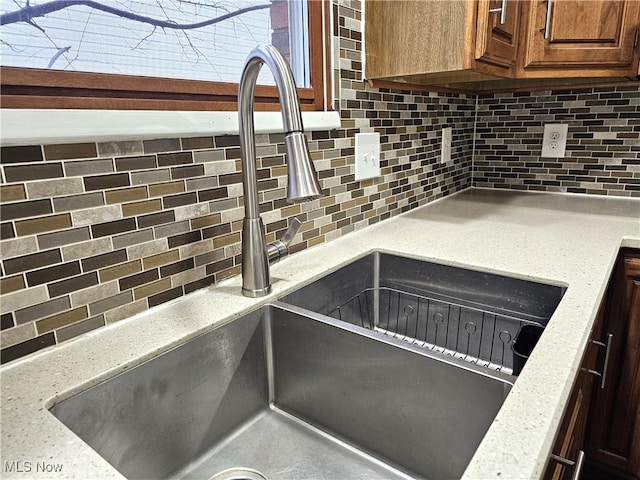 details with tasteful backsplash, light stone countertops, and sink