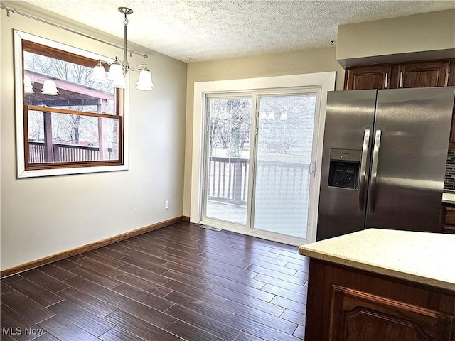 kitchen featuring hanging light fixtures, dark brown cabinets, a textured ceiling, dark hardwood / wood-style flooring, and stainless steel fridge with ice dispenser