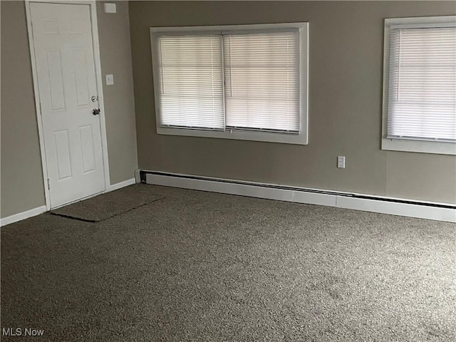 spare room with carpet floors and a baseboard heating unit