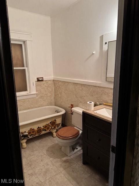 bathroom with tile walls, vanity, a bath, tile patterned floors, and toilet