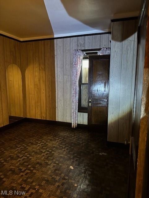 spare room with dark parquet flooring and wooden walls