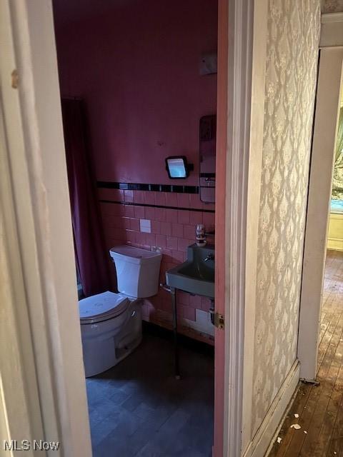 bathroom featuring hardwood / wood-style floors, sink, tile walls, and toilet