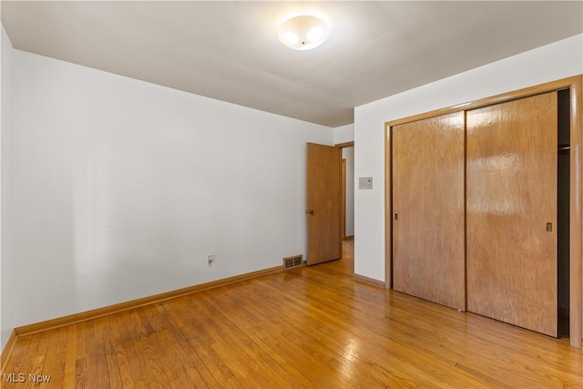 unfurnished bedroom with light hardwood / wood-style floors and a closet