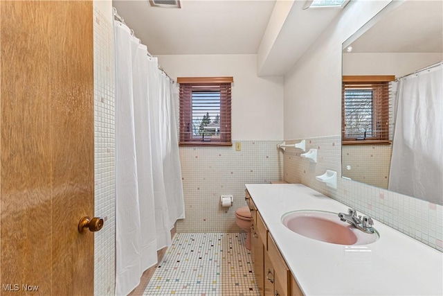 bathroom featuring vanity, a healthy amount of sunlight, tile walls, and tile patterned floors