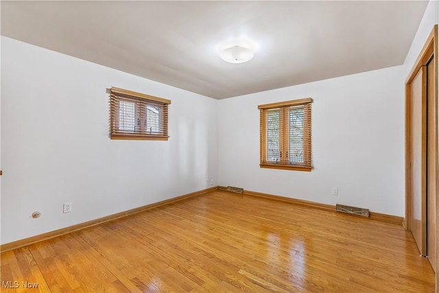 unfurnished bedroom with multiple windows, light hardwood / wood-style floors, and a closet