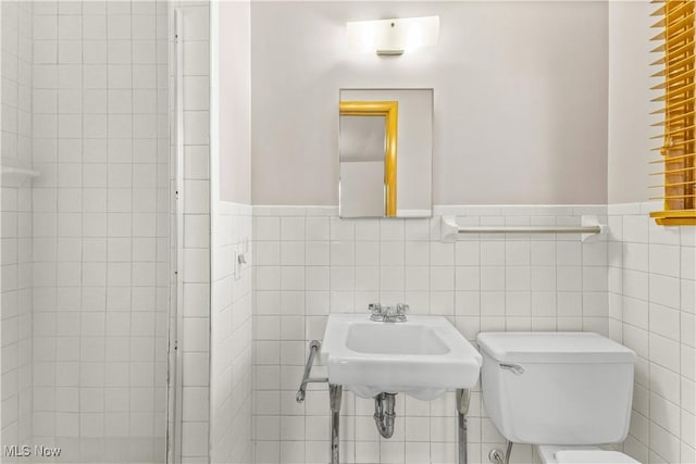 bathroom with sink, tile walls, and toilet