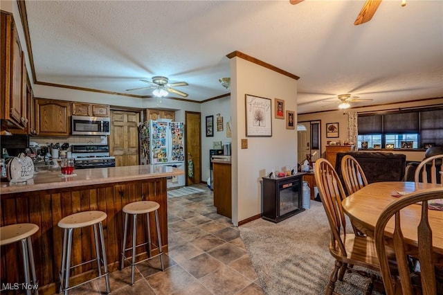 kitchen with stainless steel appliances, ornamental molding, ceiling fan, and kitchen peninsula