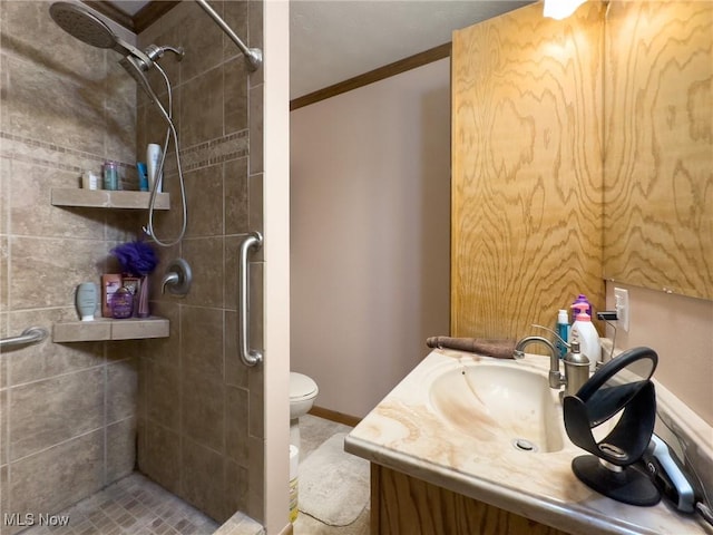 bathroom featuring vanity, ornamental molding, toilet, and tiled shower