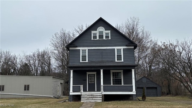 view of property featuring an outbuilding, a porch, a garage, and a front lawn