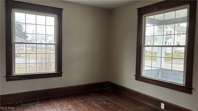 spare room featuring a wealth of natural light and dark hardwood / wood-style flooring