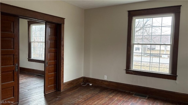 empty room featuring a healthy amount of sunlight and dark hardwood / wood-style floors