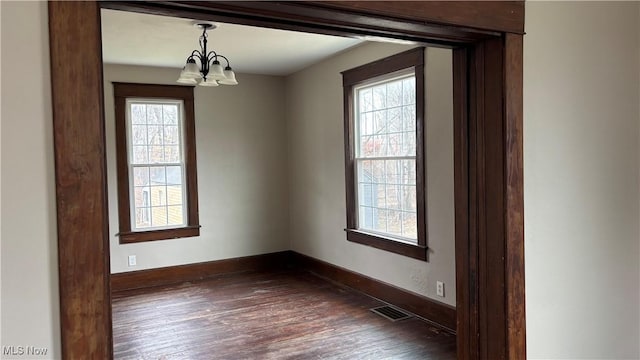 spare room with dark hardwood / wood-style flooring and a notable chandelier