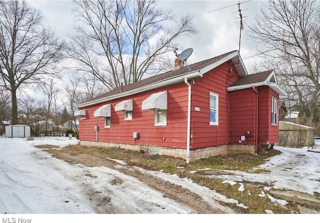 view of snow covered exterior with a shed