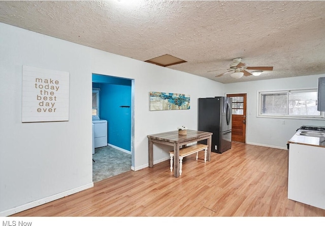 kitchen with black refrigerator, washer / dryer, a textured ceiling, and light wood-type flooring