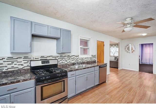 kitchen with sink, backsplash, stainless steel appliances, light hardwood / wood-style floors, and a textured ceiling