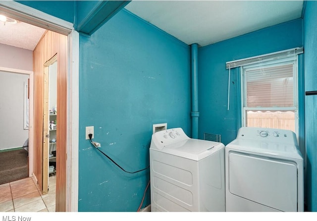 clothes washing area featuring light tile patterned floors and washer and clothes dryer