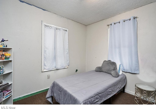 bedroom featuring dark carpet and a textured ceiling
