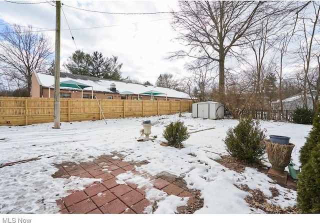 snowy yard featuring a shed