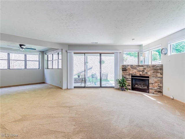 unfurnished living room featuring light colored carpet, a stone fireplace, and a textured ceiling