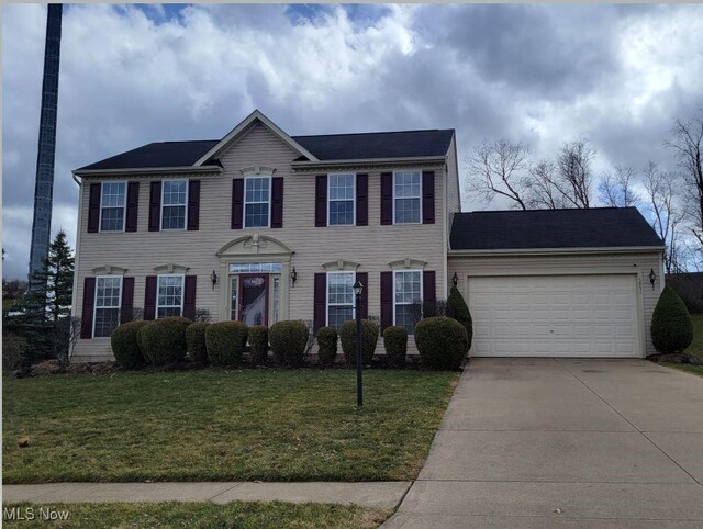colonial house with a front lawn, concrete driveway, and a garage