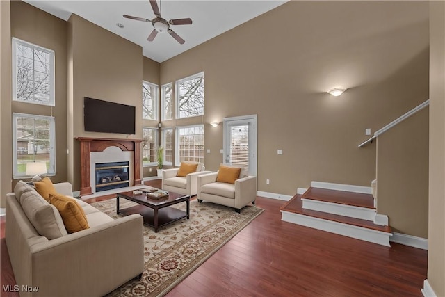 living room featuring a wealth of natural light, wood-type flooring, ceiling fan, and a high ceiling