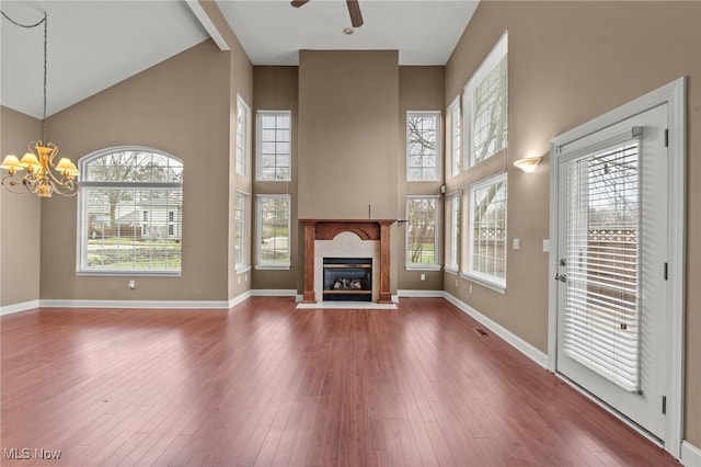 unfurnished living room featuring ceiling fan with notable chandelier, high vaulted ceiling, hardwood / wood-style floors, and a fireplace