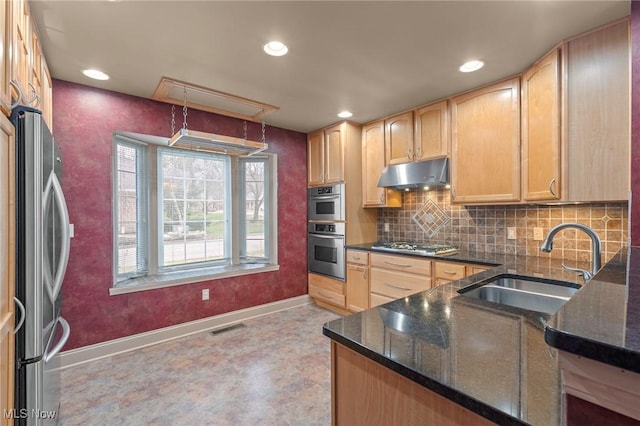 kitchen with light brown cabinetry, sink, backsplash, dark stone counters, and stainless steel appliances