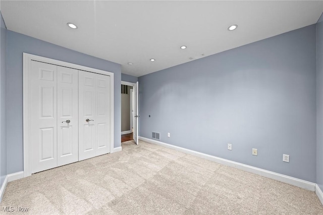 unfurnished bedroom featuring light carpet and a closet