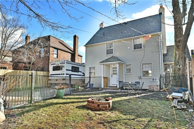 back of property with a fire pit and a lawn