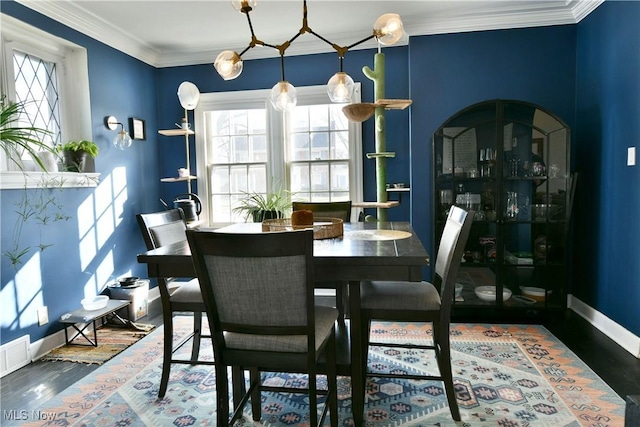 dining room with dark hardwood / wood-style flooring, plenty of natural light, and ornamental molding