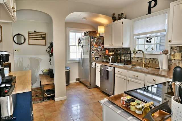 kitchen with sink, white cabinetry, tasteful backsplash, light tile patterned floors, and stainless steel appliances