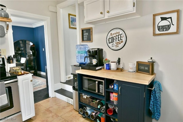 bar with crown molding, butcher block counters, stainless steel range with electric cooktop, and white cabinets