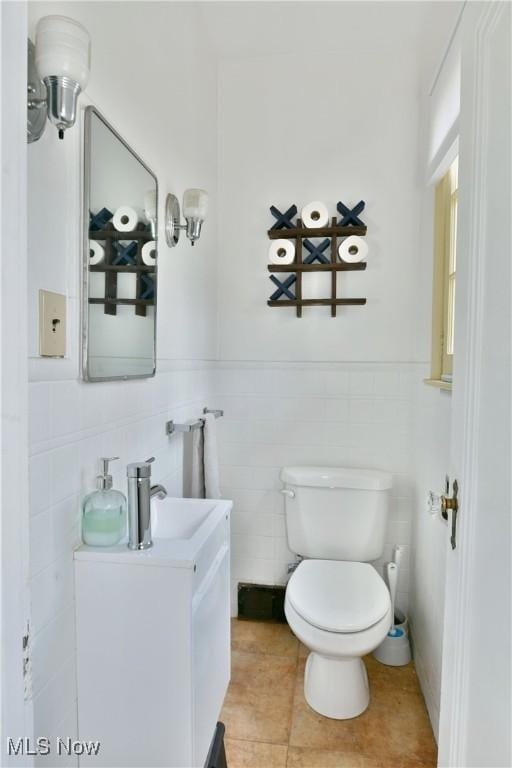 bathroom featuring vanity, tile patterned flooring, tile walls, and toilet