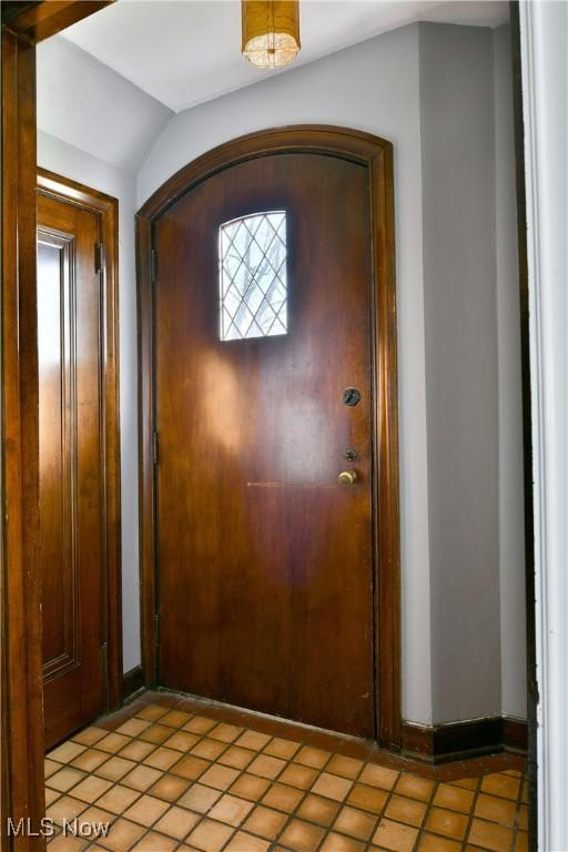 entrance foyer featuring light tile patterned flooring and lofted ceiling