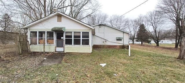 rear view of house with a yard and a sunroom