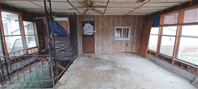 misc room featuring wooden walls and concrete flooring