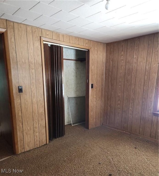 unfurnished bedroom with carpet floors and wood walls