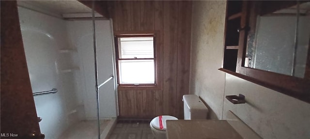 bathroom featuring toilet, wood walls, and walk in shower