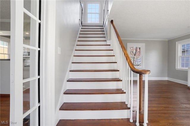 stairway featuring crown molding, wood-type flooring, and a textured ceiling