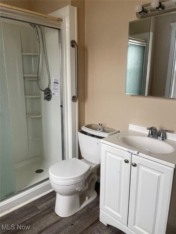 bathroom featuring vanity, hardwood / wood-style flooring, a shower with door, and toilet