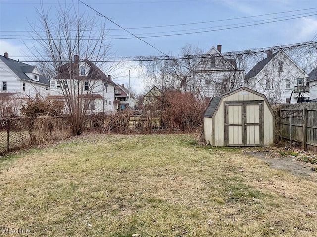 view of yard with fence, a storage unit, and an outbuilding