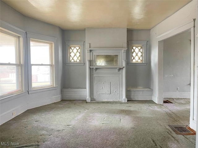 unfurnished living room featuring carpet flooring, visible vents, and baseboards