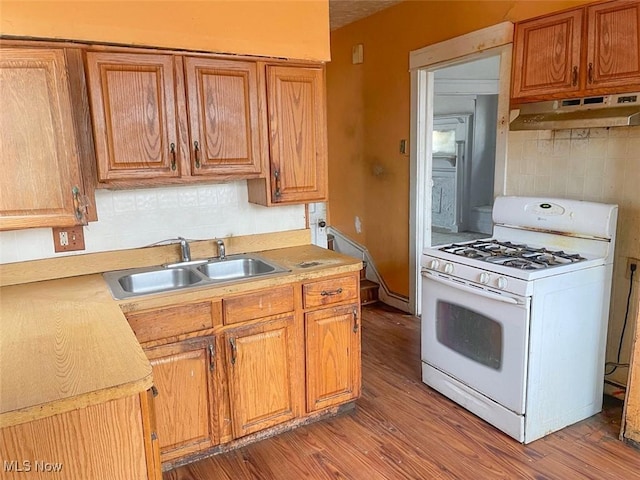 kitchen featuring white range with gas cooktop, light wood-style floors, light countertops, under cabinet range hood, and a sink